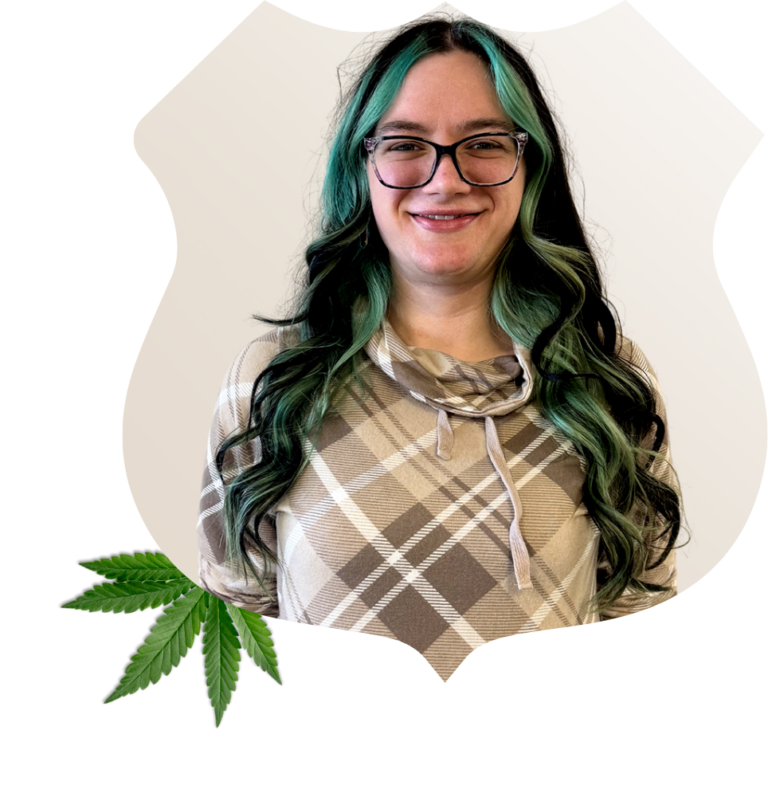 Kayla Nettles – St. Peters Store Manager Portrait of Kayla Nettles, store manager at Root 66 Dispensary Des Peres. She has long, wavy green-highlighted hair. A cannabis leaf is in the bottom corner of the image.